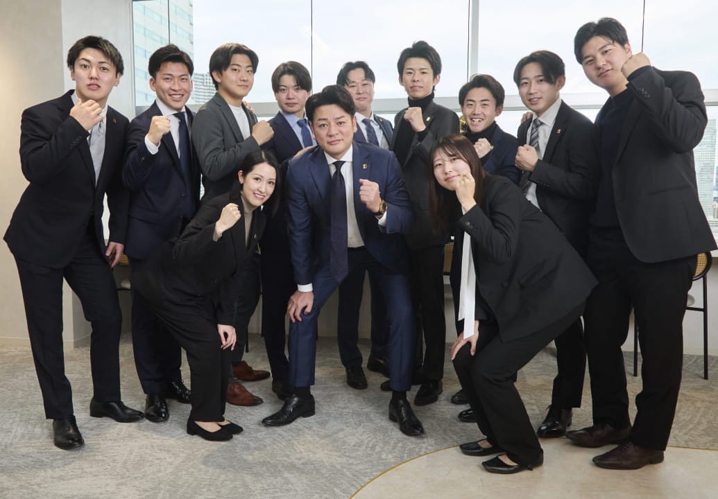たくさんの社員が集まってガッツポーズをしている