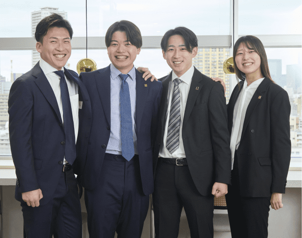 4人の社員が仲良く並んでいる様子