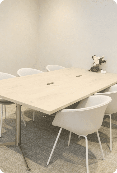 シンプルで落ち着いた会議スペース。長方形の木製テーブルと白いチェアが配置されている。